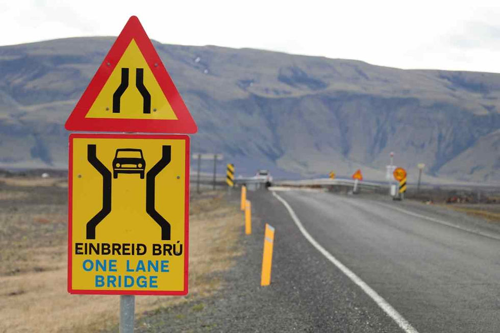 Plano detalle de una señal de tráfico islandesa donde se observa una inscripción en idioma local e inglés indicando la proximidad de un puente de un solo carril.