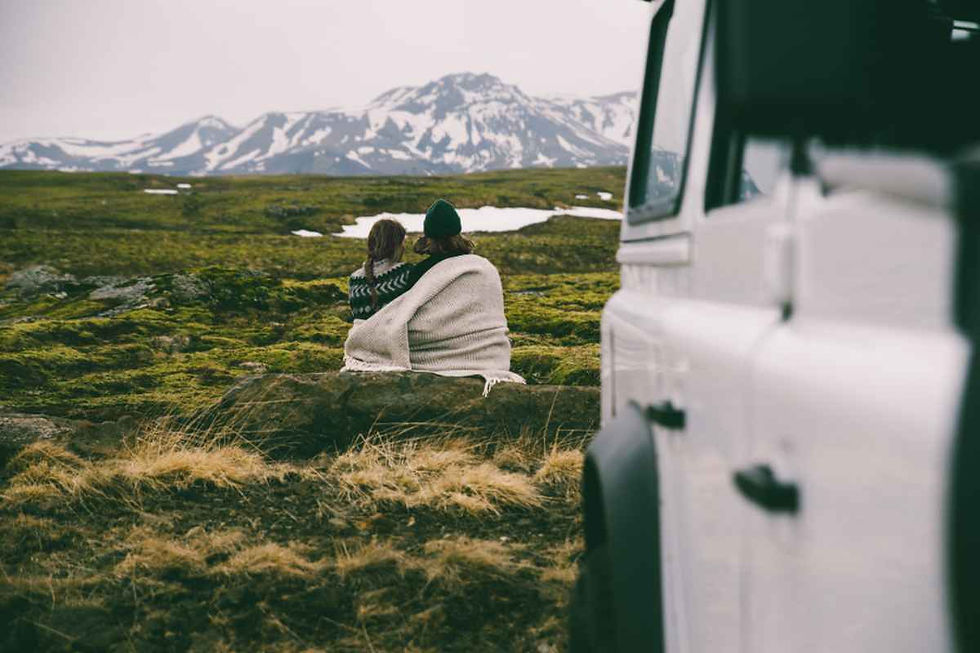 Una pareja disfruta de un descanso fuera de su camper frente a unas montañas en Islandia.