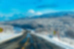 Winter road on the E6 in Norway with 50 km/h speed limit signs and snowy forest landscape.