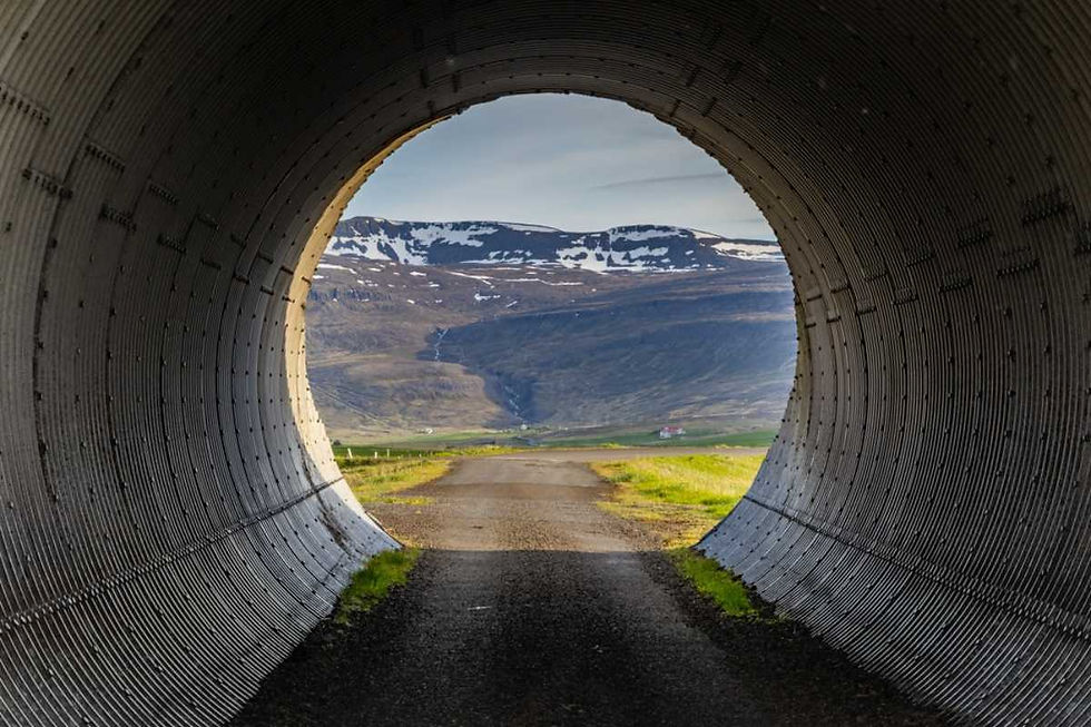 Carretera vista desde un túnel en los Fiordos del Oeste de Islandia con montañas al fondo.