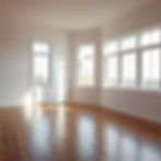 A bright, empty room with windows, wooden floors, filled with soft natural light, clean fl