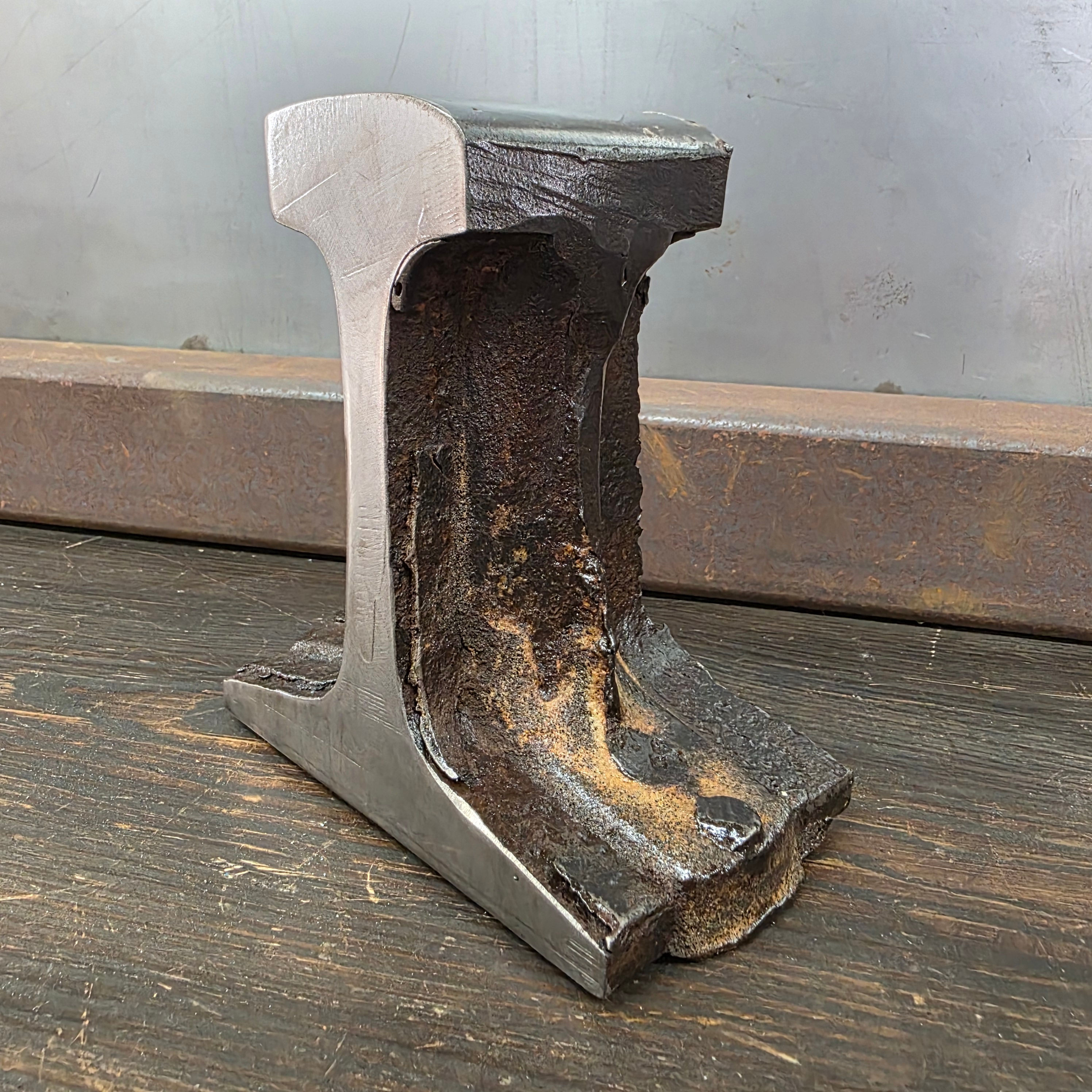 Hand-forged steel rail anvil cut-off by Colonial Metalworks. Raw industrial finish showcasing hammer marks, heat scale, and o