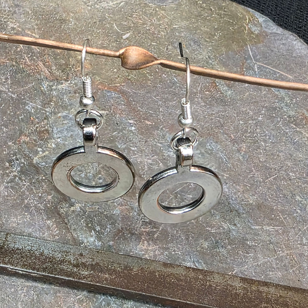 Handmade stainless steel washer dangle earrings hanging from a copper display rod