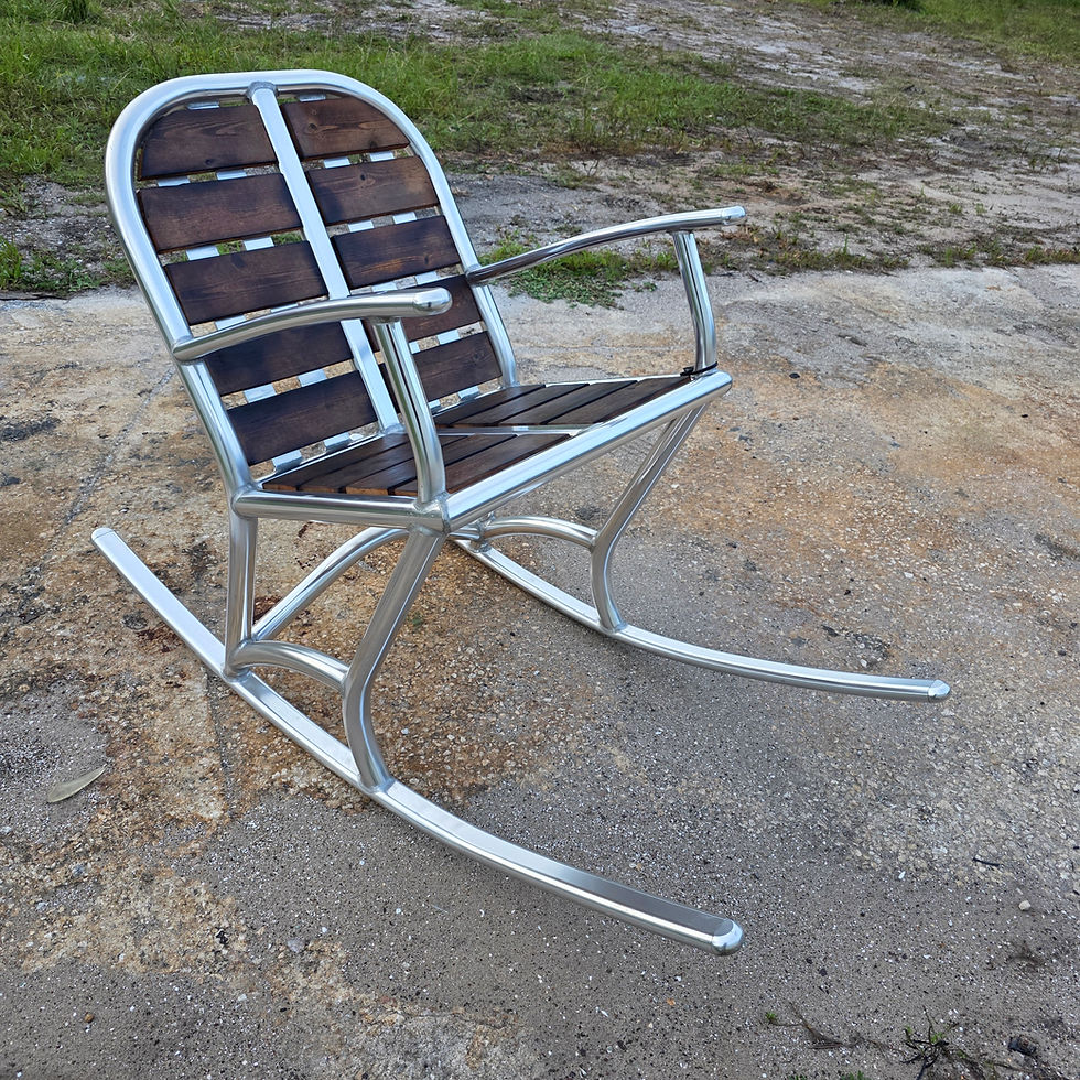 Coastal outdoor rocking chair with welded aluminum frame and dark wood slats