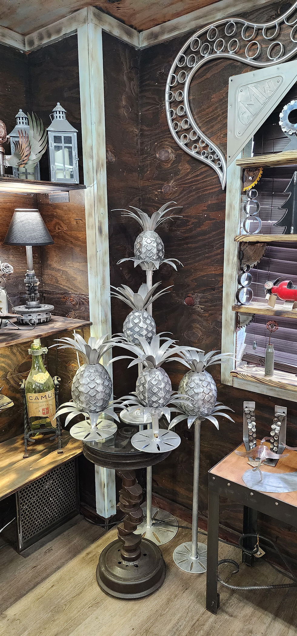 Five raw aluminum pineapple torches arranged on varied height landscape poles in a clean showroom studio.