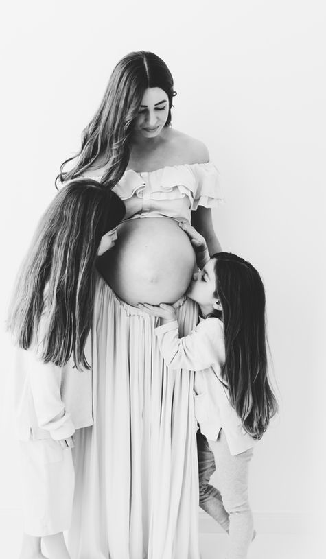 Zwei Kinder küssen den Babybauch beim Babybauchshooting Hildesheim.