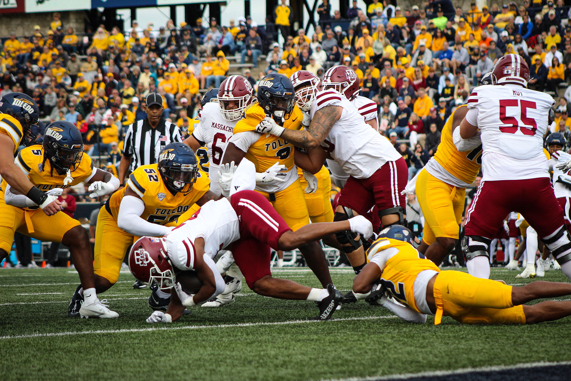 The Rocket’s defensive line takes down a UMass player as Toledo premieres its new gold-colored jerseys in the Sept. 7 game.