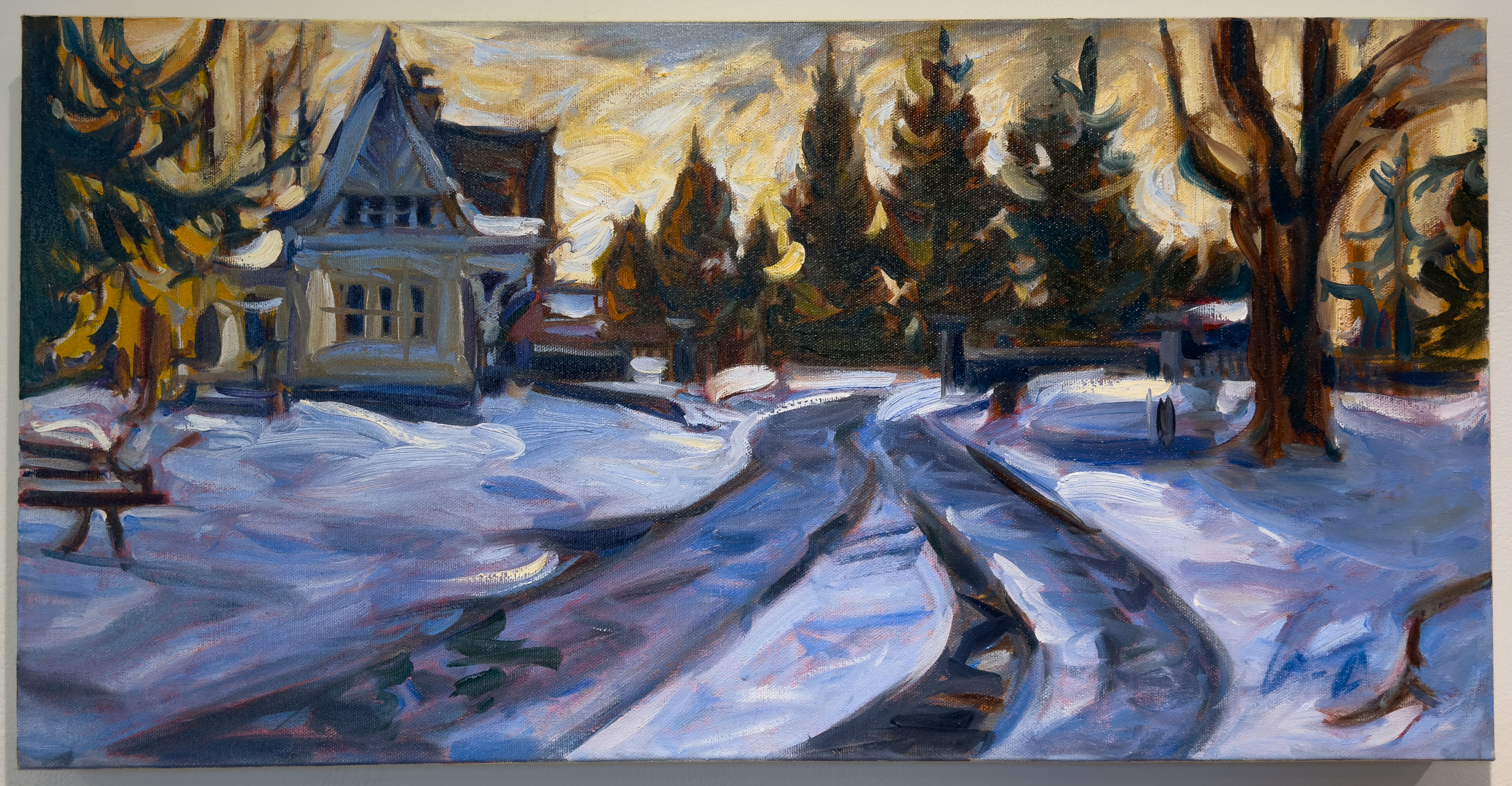 Tire tracks in snow leading up to a small gatehouse with a winding driveway.