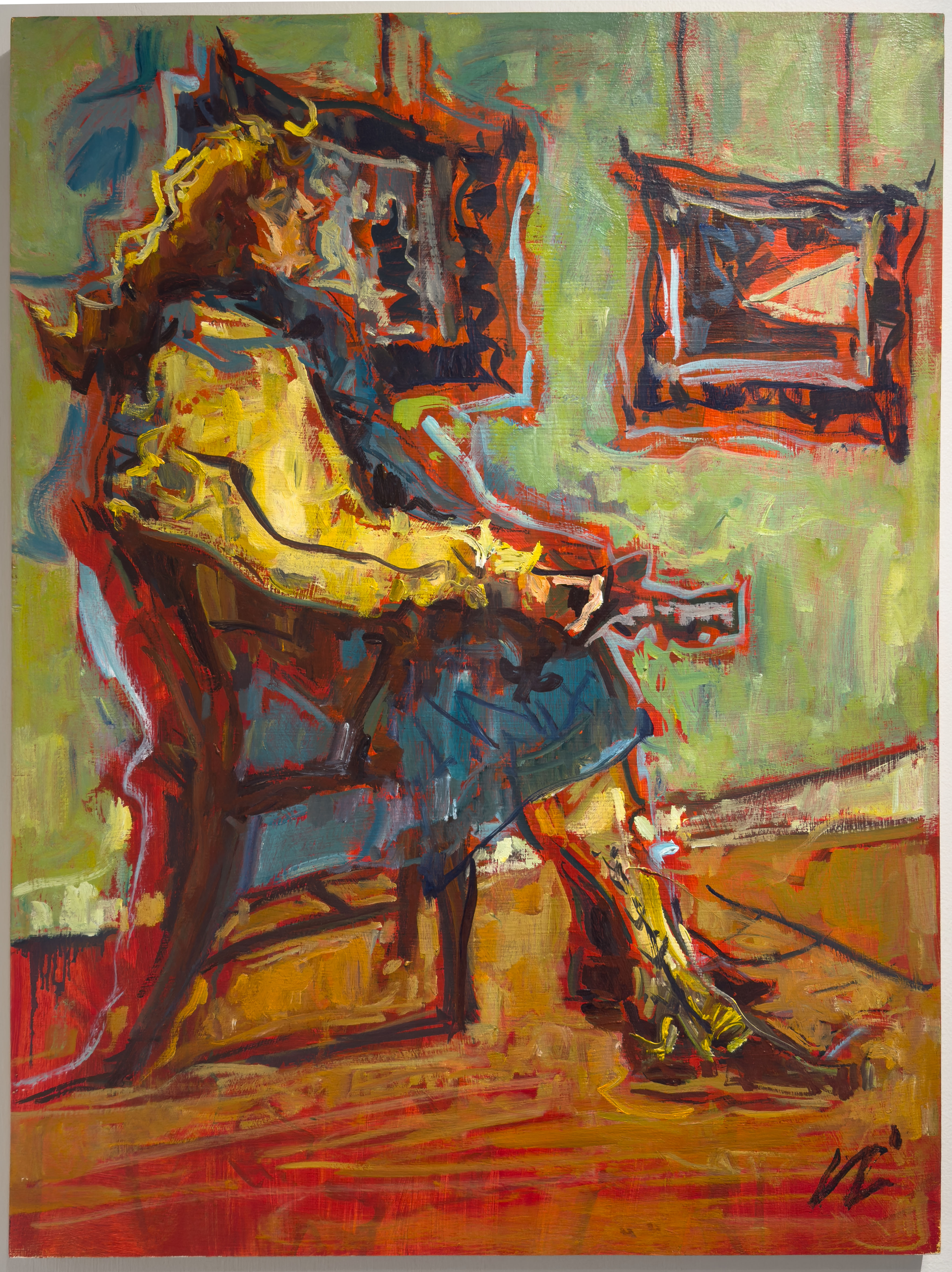 A woman in a yellow jacket and blue dress sitting looking at work on a gallery wall.