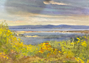 A bright summer shoreline with a cloudy blue sky and warm flowery greenery.