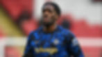 Axel Disasi in a blue geometric-patterned Chelsea jersey with "trivago" text, serious expression, blurred stadium background.