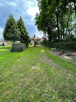 Grüner Rasenweg mit Bäumen und Gebäude im Hintergrund