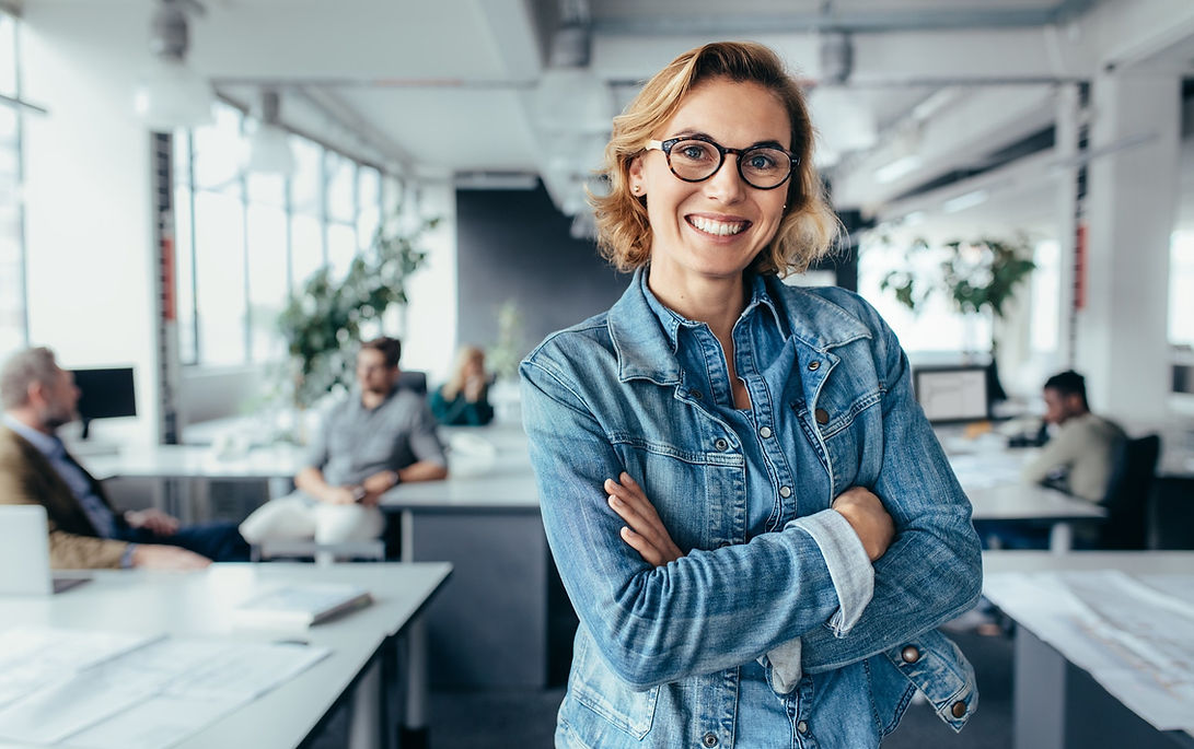 Lächelnde Frau mit Brille im Büro, verschränkte Arme, Start. Plus Placement GmbH.