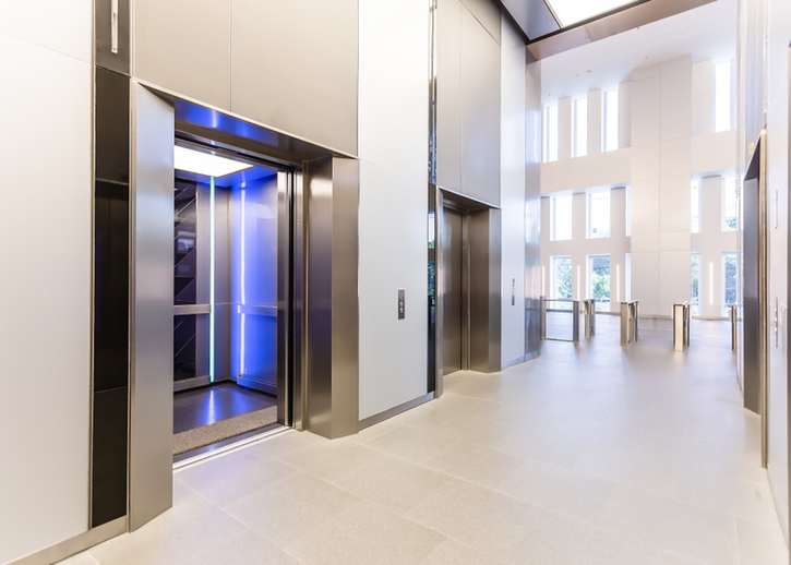
Dans le hall de l'immeuble, deux ascenseurs accueillent les occupants, leurs portes ouvertes laissant entrevoir l'opportunité de voyages verticaux. Une invitation à l'ascension, ces portails métalliques prêts à dévoiler les étages de la vie quotidienne.