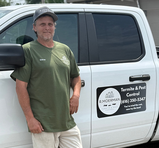 Technician standing by a white pest control service truck.