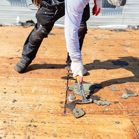Worker prying up old roofing material