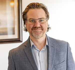 Mike Zeilstra smiling, with glasses and a beard in a grey blazer