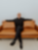Chris Carr in black shirt sitting on brown leather sofa