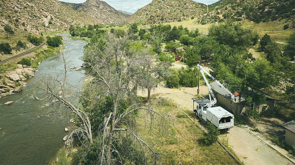 Utility truck with boom arm near river and mountains