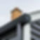 Black gutter system on a house with dark siding and brick chimney