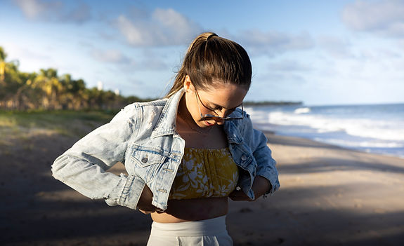 modelo na praia, olhando sua propia roupa durante uma cessão de fotos.