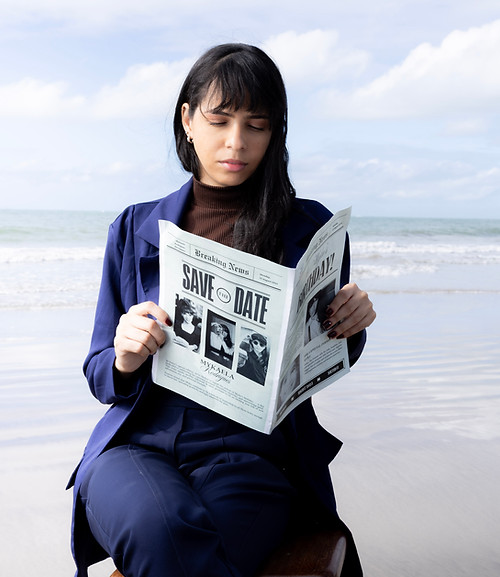 mulher de terno na praia seguando um jornal