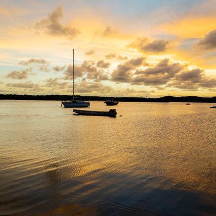 Por do sol na praia com barco a vela atracado 