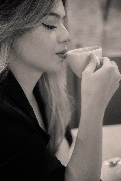 a foto retrata a modelo de perfil tomando um café