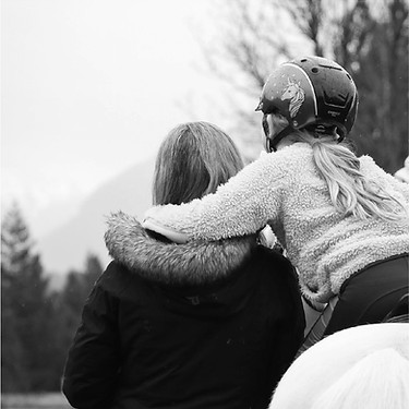 A child embracing another person on a horse