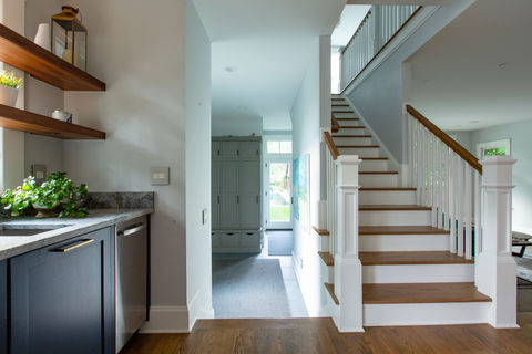 Modern entryway with wood stairs, a wet bar, and floating shelves.
