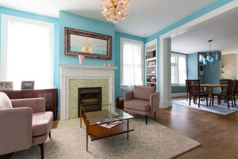 Spacious blue living room with fireplace, two pink armchairs, coffee table.