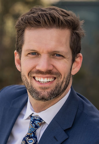 Portrait of Tyler Quesnel, an immigration lawyer in Massachusetts, smiling widely at the camera. 
