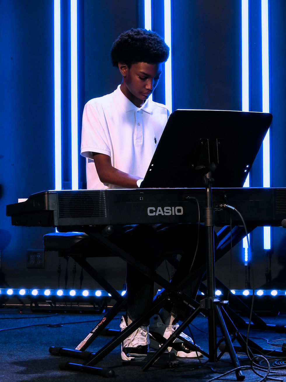 A boy in a white shirt playing piano