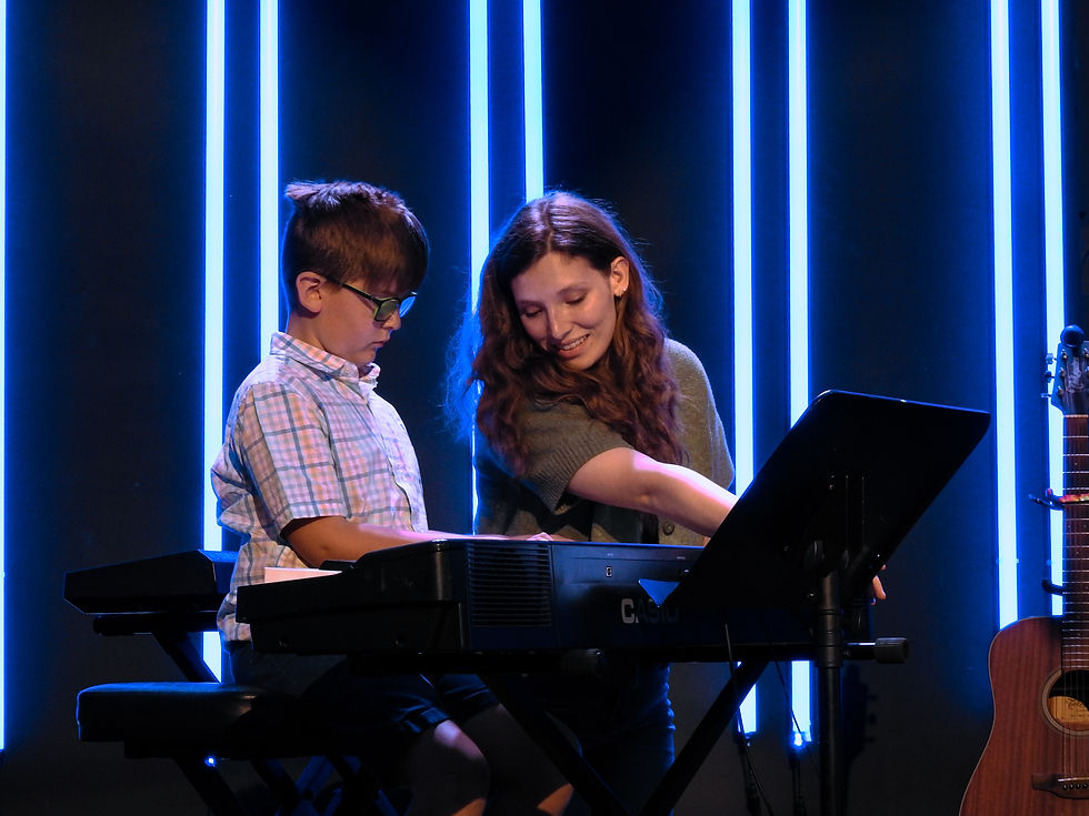 Little boy and female music teacher sitting at piano