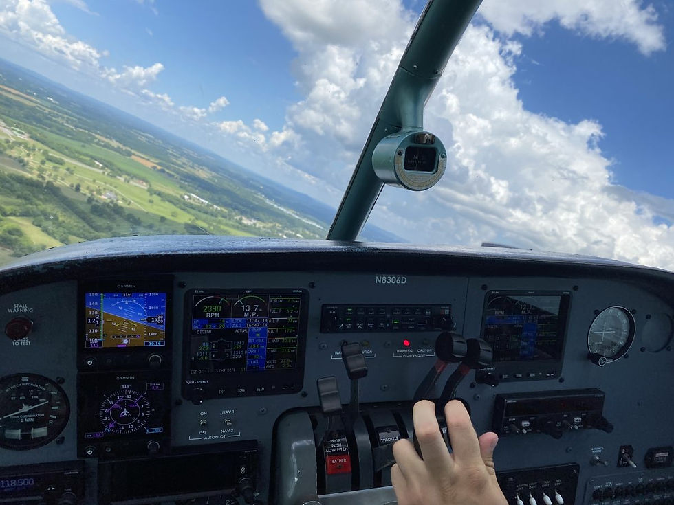 Hand on airplane controls in cockpit, flying above green landscape and clouds. Instrument panel displays data. Airborne adventure.