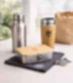 Nachhaltige Werbemittel der Remise GmbH: Brotdose aus Edelstahl, Thermobecher und Trinkflasche mit Logo-Gravur.
