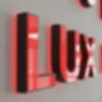 Rot hinterleuchtete 3D-LED-Buchstaben „LUX“ an einer grauen Wand.