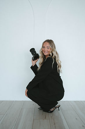 Portrait of Hannah Reasoner Photography squatting with camera