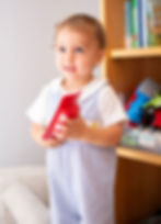 A toddler boy smiling and holding a toy