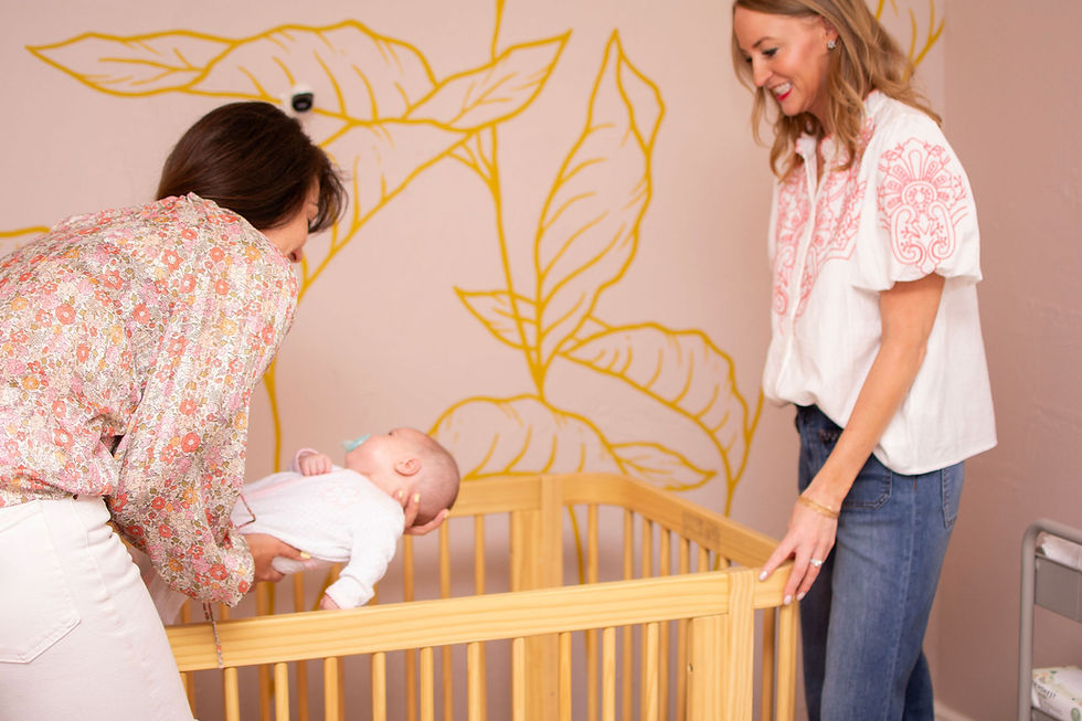 A nanny helping a mom lay a newborn down for a nap in a crib