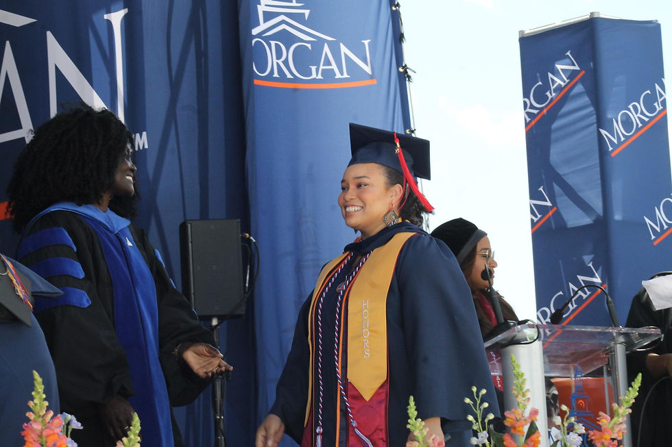 Lillian Stephens, a woman in her 30s, walks across the stage wearing her cap, gown, mortarboard and sashes during graduation ceremony at Morgan State University.