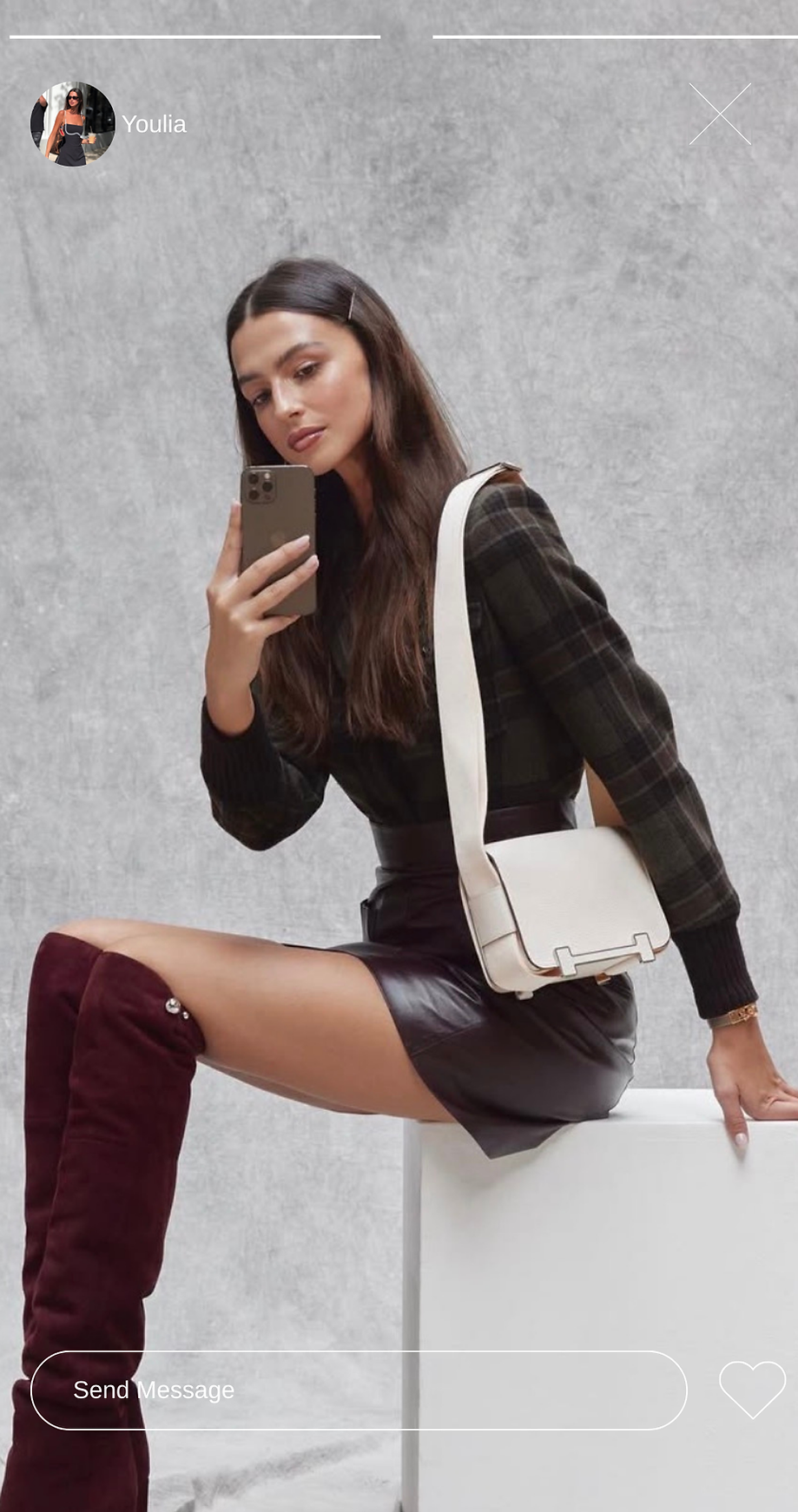 Woman taking a selfie in dark outfit and tall boots