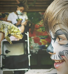 A little boy comes noe to nose with a newt while he smile at his birthday party