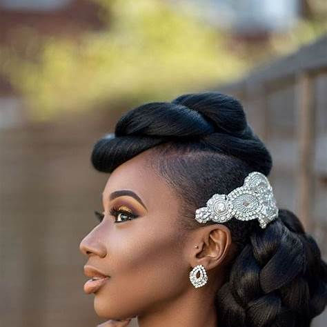 Gros plan sur une femme portant des vanilles plates (twists) soigneusement réalisées, regroupées en un chignon bas. La coiffure est sublimée par un bijou capillaire élégant, mettant en valeur son style chic et raffiné. L’arrière-plan flou accentue la beauté de la coiffure.