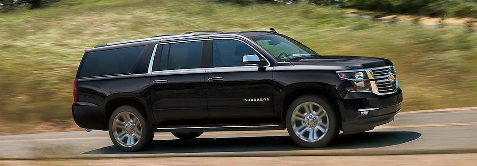 A black Suburban moving fast on a road.