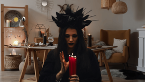 Background: Metaphysical Shop with candles, pendulums, triple crescent moon, crystals, a table, reading chair, herbs. Foreground: Woman in all black and an elaborate black rose head dress gazing at a bundle of long red candles. Marketing for the Too Niche, Too Weird Spiritual Business (My Why). Helping Spiritual Practitioners Build Stable Businesses for Unstable Times. Gem Blackthorn Tarot Business Spiritual Marketing.