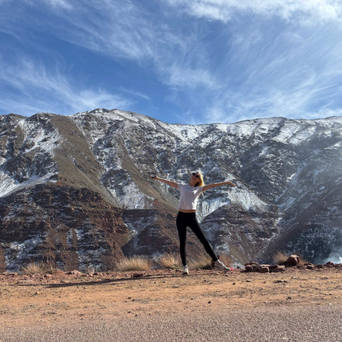 Woman by the road in front of mountains