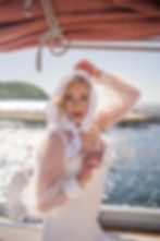 Beautiful bride, looking at the camera holding her wedding veil on a sailboat in Sister Bay