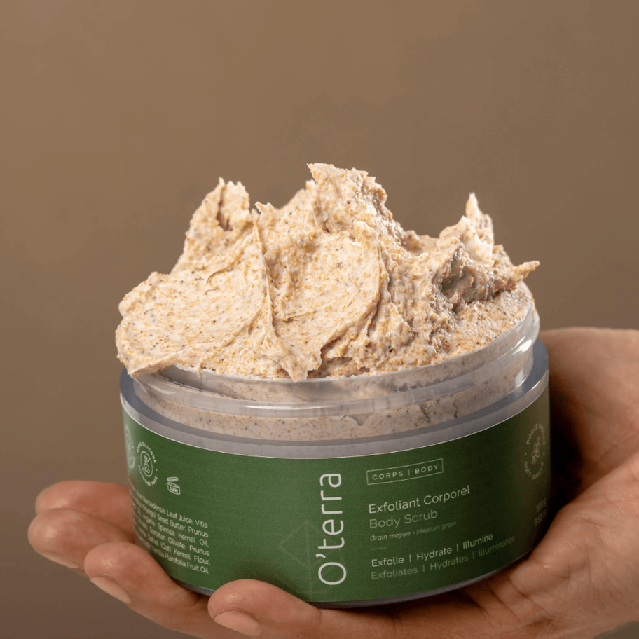 Pot d’exfoliant corporel O’terra tenu dans une main mettant en valeur sa texture riche et fouettée.