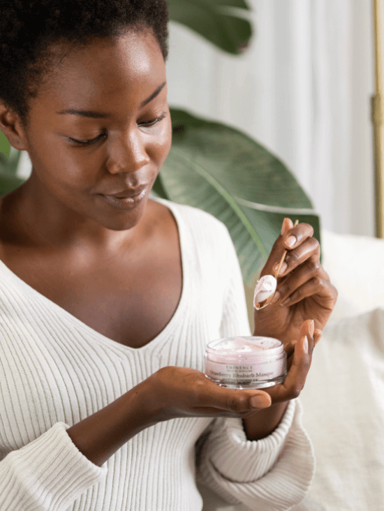 Femme tenant le masque Strawberry Rhubarb d’Eminence Organics et prelevant le produit avec une spatule